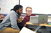 A teacher helping a student on a laptop. Links to Gifts of Life Insurance A teacher helping a student on a laptop. Links to Gifts of Life Insurance